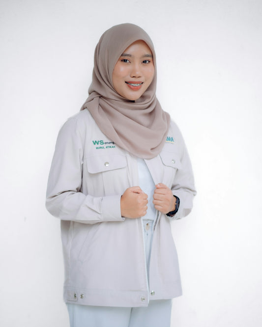 A smiling woman in a hijab and jacket is posing.